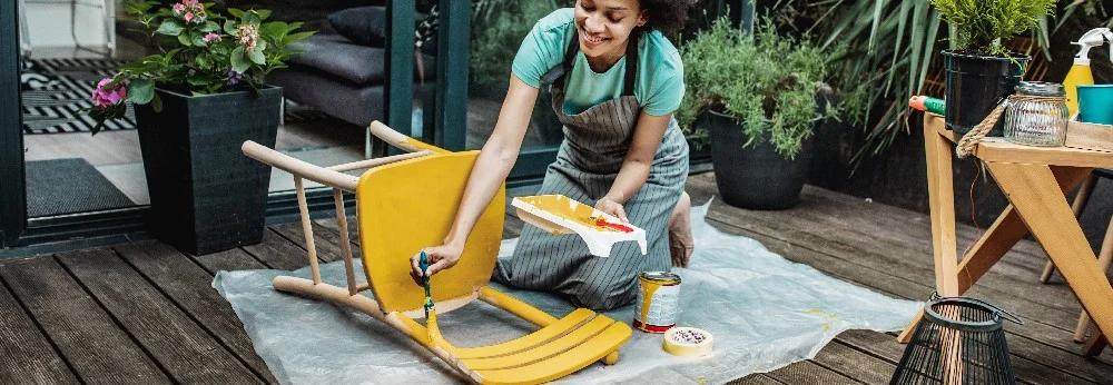 Person streicht Stuhl gelb